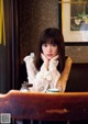 A woman sitting at a table with a cup of coffee.