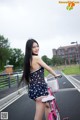 A woman standing next to a pink bike on a street.