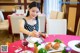 A woman sitting at a table with a plate of food.